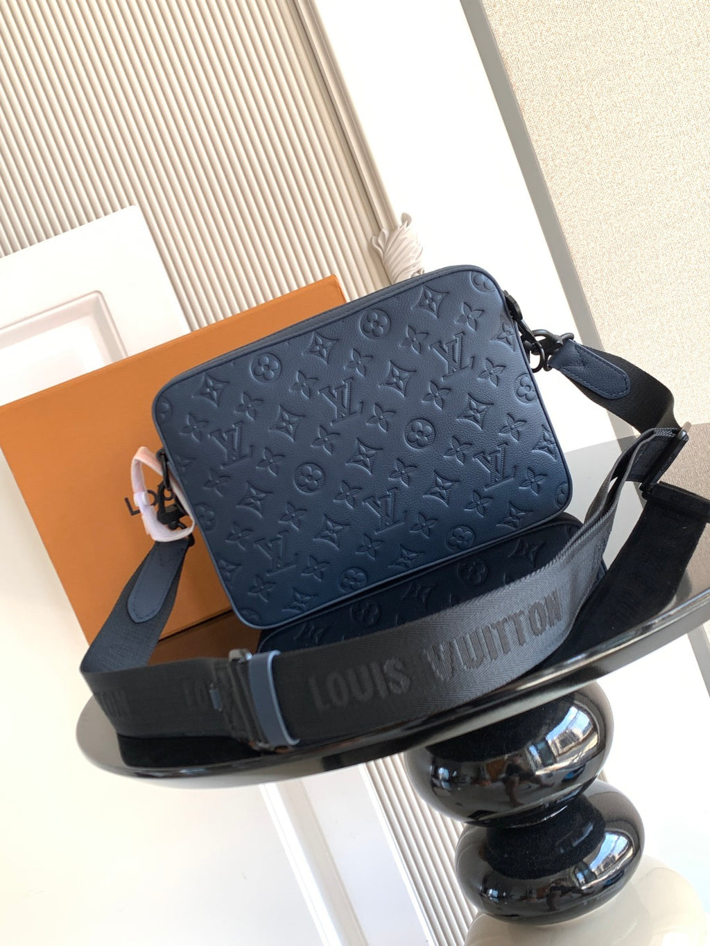 Dark blue crossbody bag with logo embossing and shoulder strap