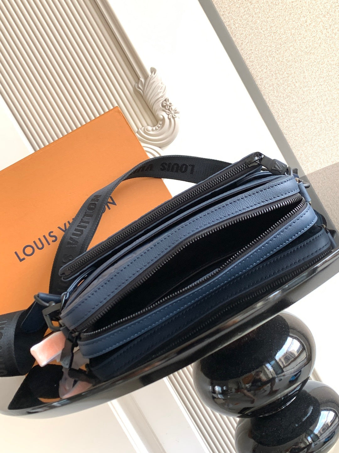 Dark blue crossbody bag with multiple zip sections and leather strap