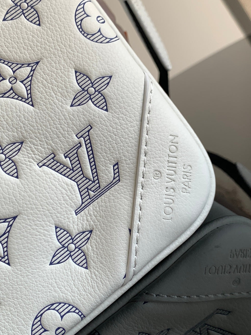 Louis Vuitton bag corner close-up with blue monogram flowers and embossed logo