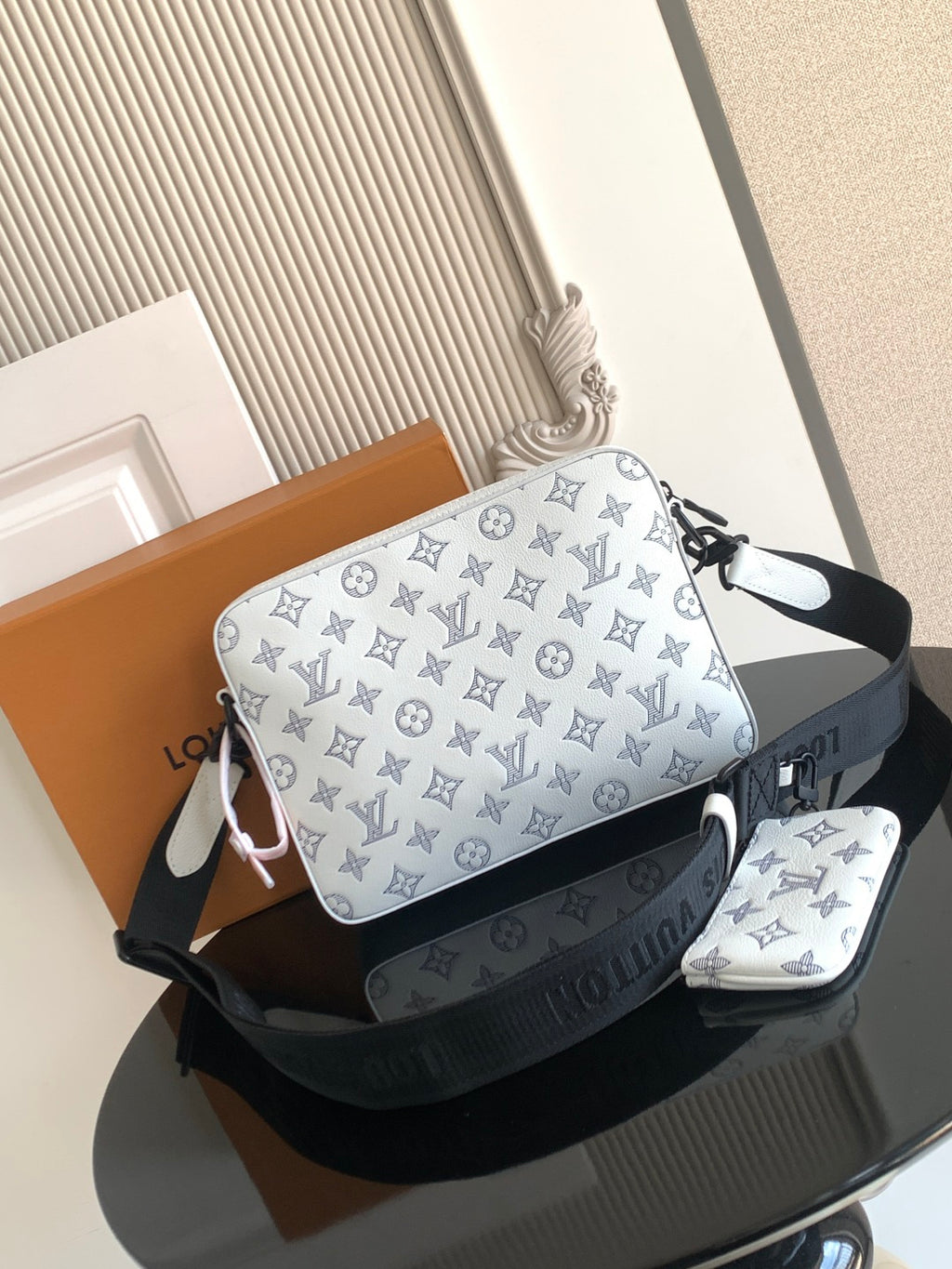 Crossbody bag with blue monogram print, black shoulder strap and small matching pouch