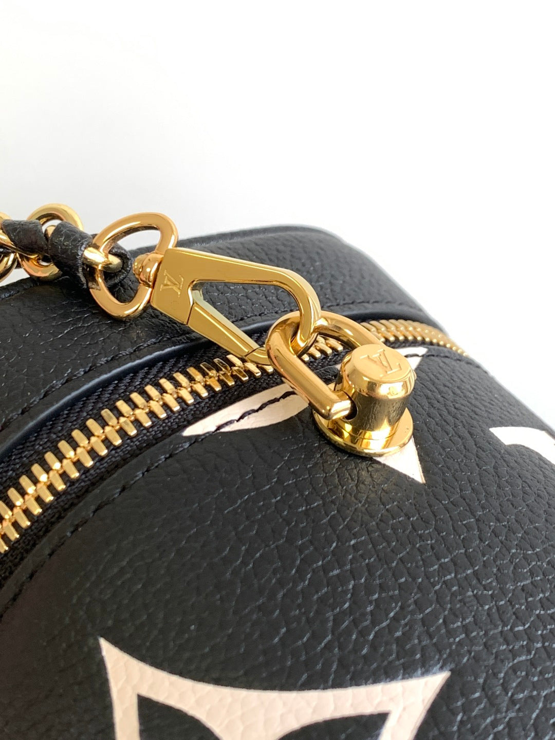 Louis Vuitton monogram bag close-up: gold clasp and zipper hardware on black leather