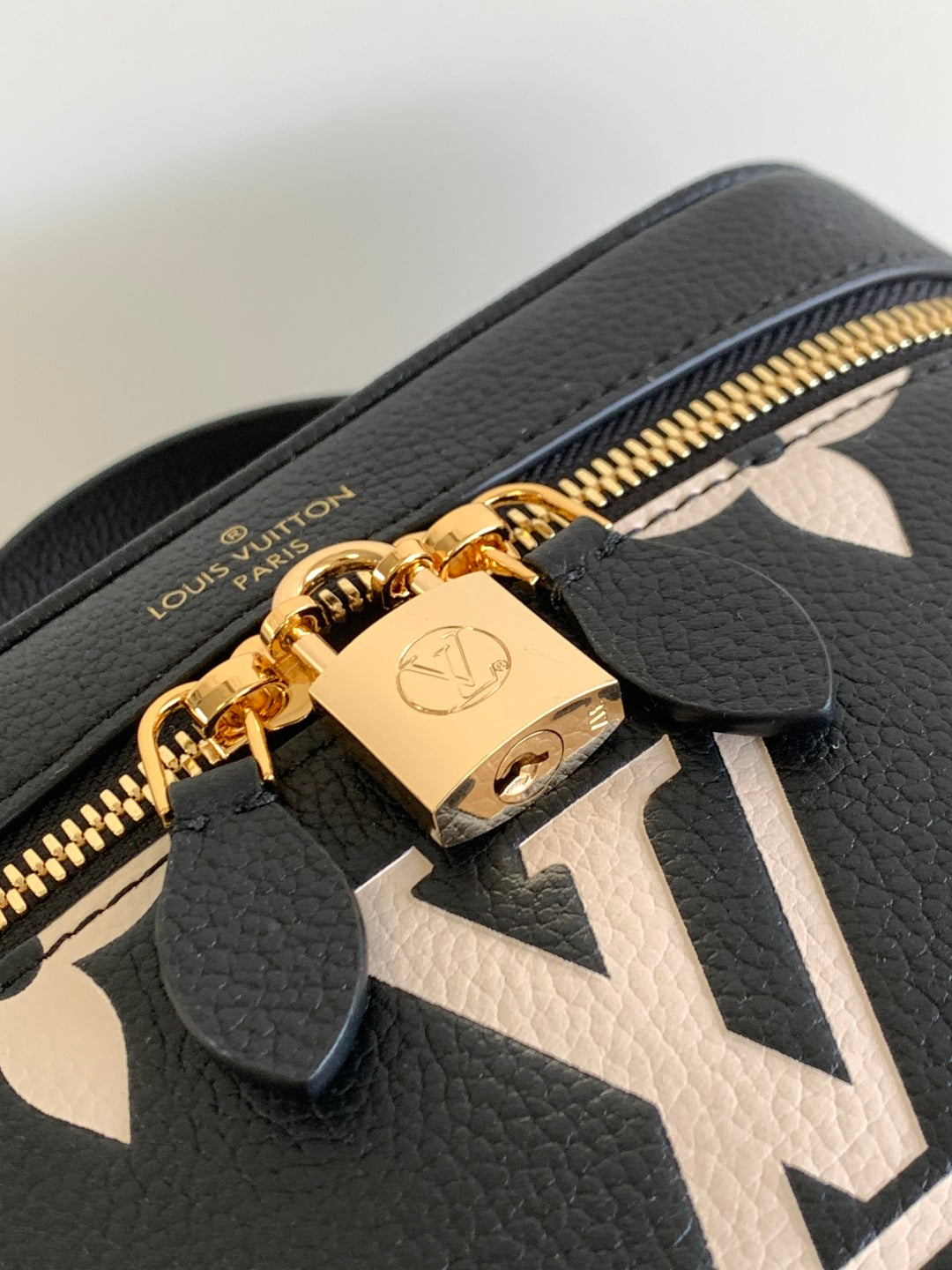 Louis Vuitton monogram bag close-up: black textured leather with gold zipper pull