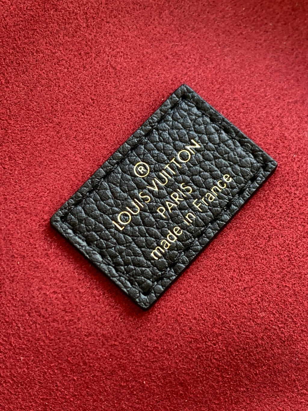 Louis Vuitton label card on black leather with “Louis Vuitton Paris” text