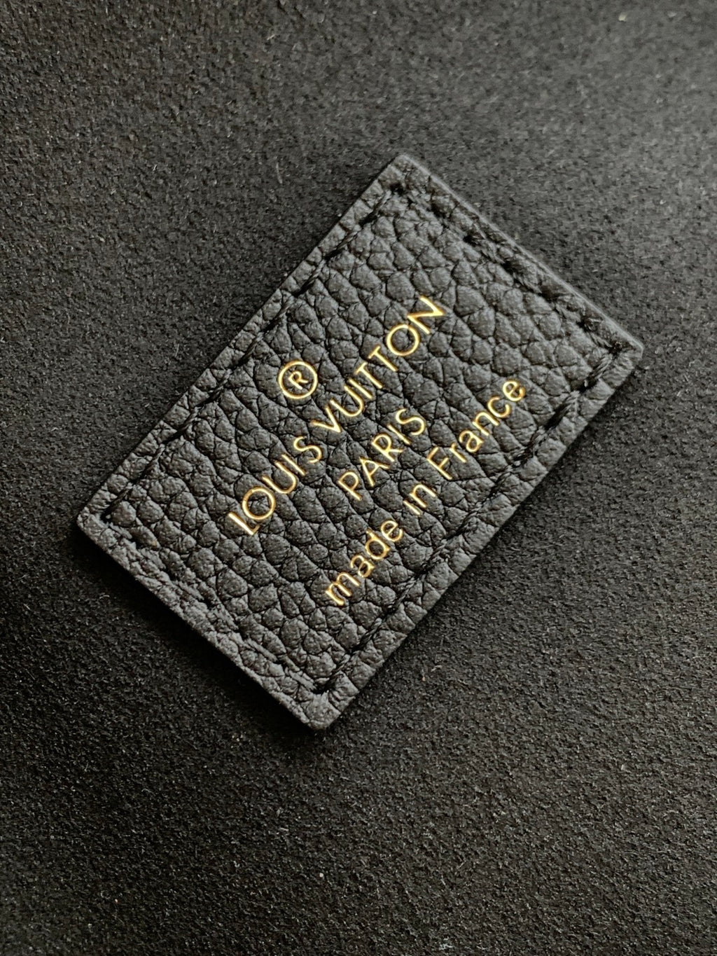 Black leather Louis Vuitton card holder label with gold embossed logo