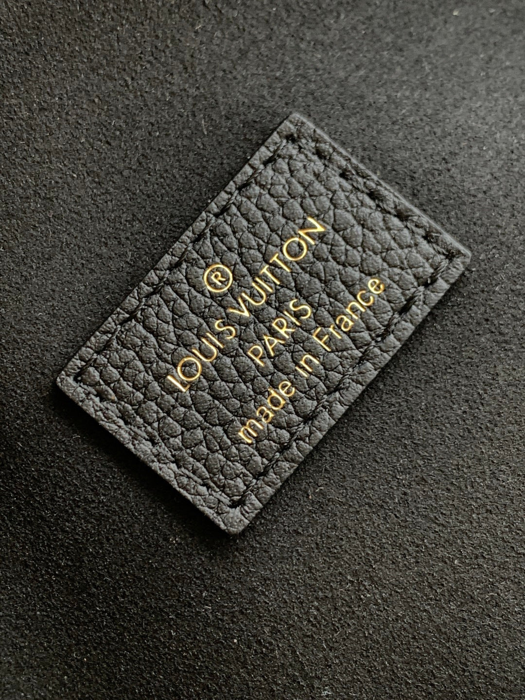 Black leather Louis Vuitton card holder label with gold embossed logo