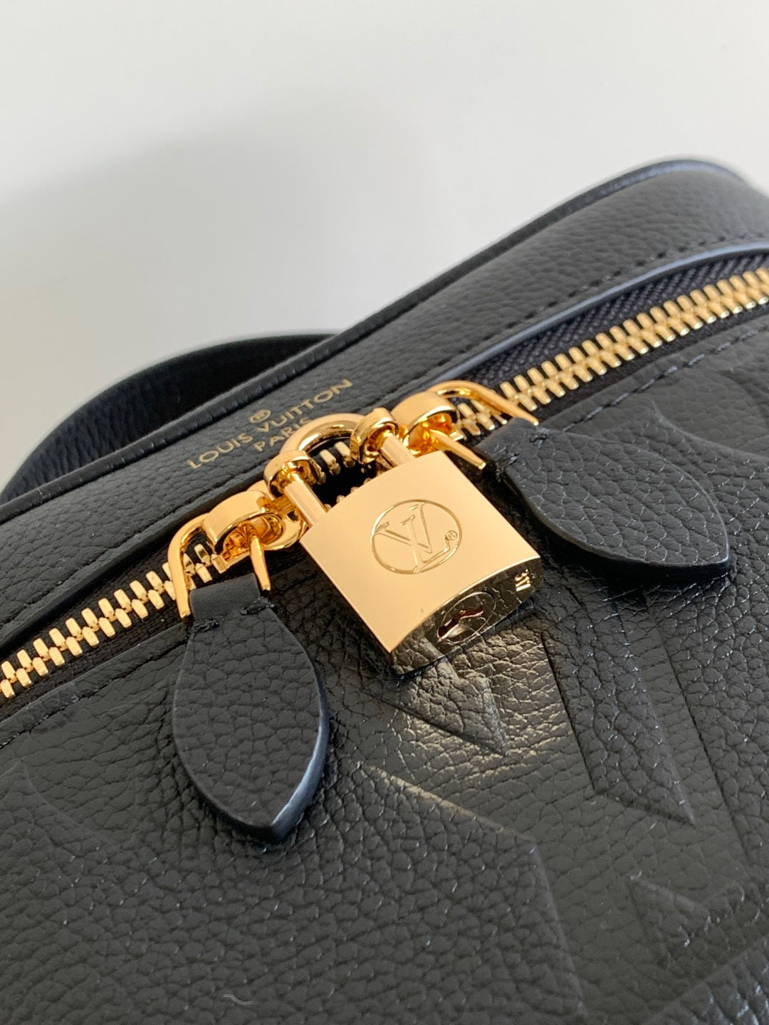 Black leather Louis Vuitton bag close-up with gold zipper pull and signature lock