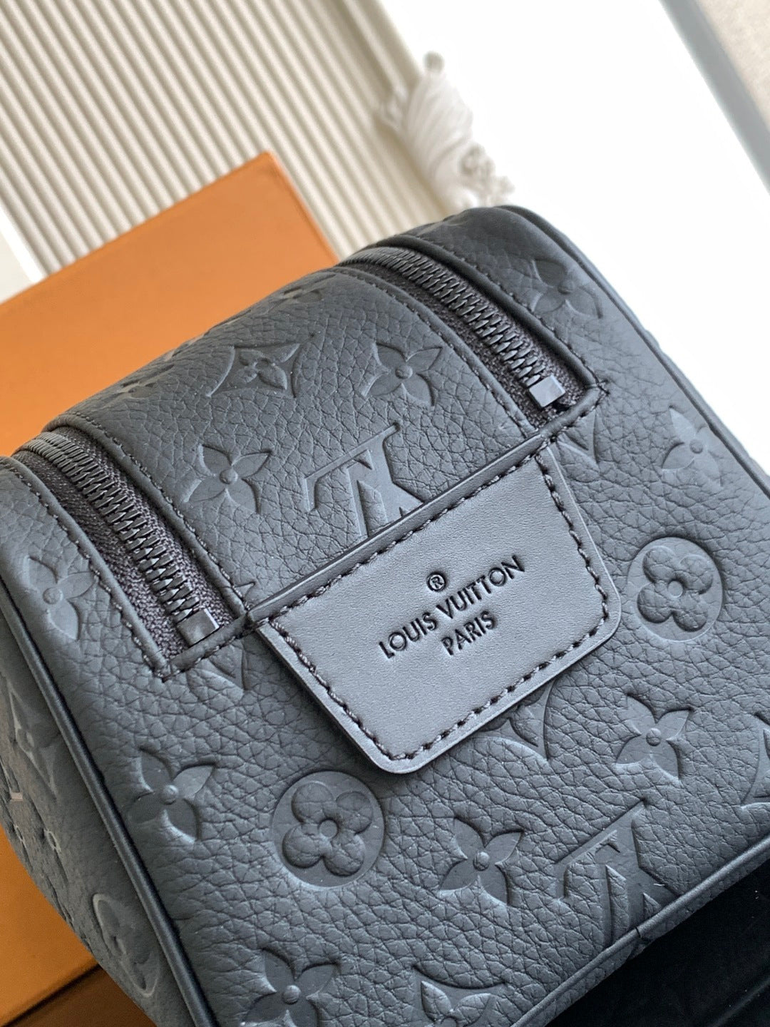 Louis Vuitton bag close-up with gray leather texture and stitched brand patch