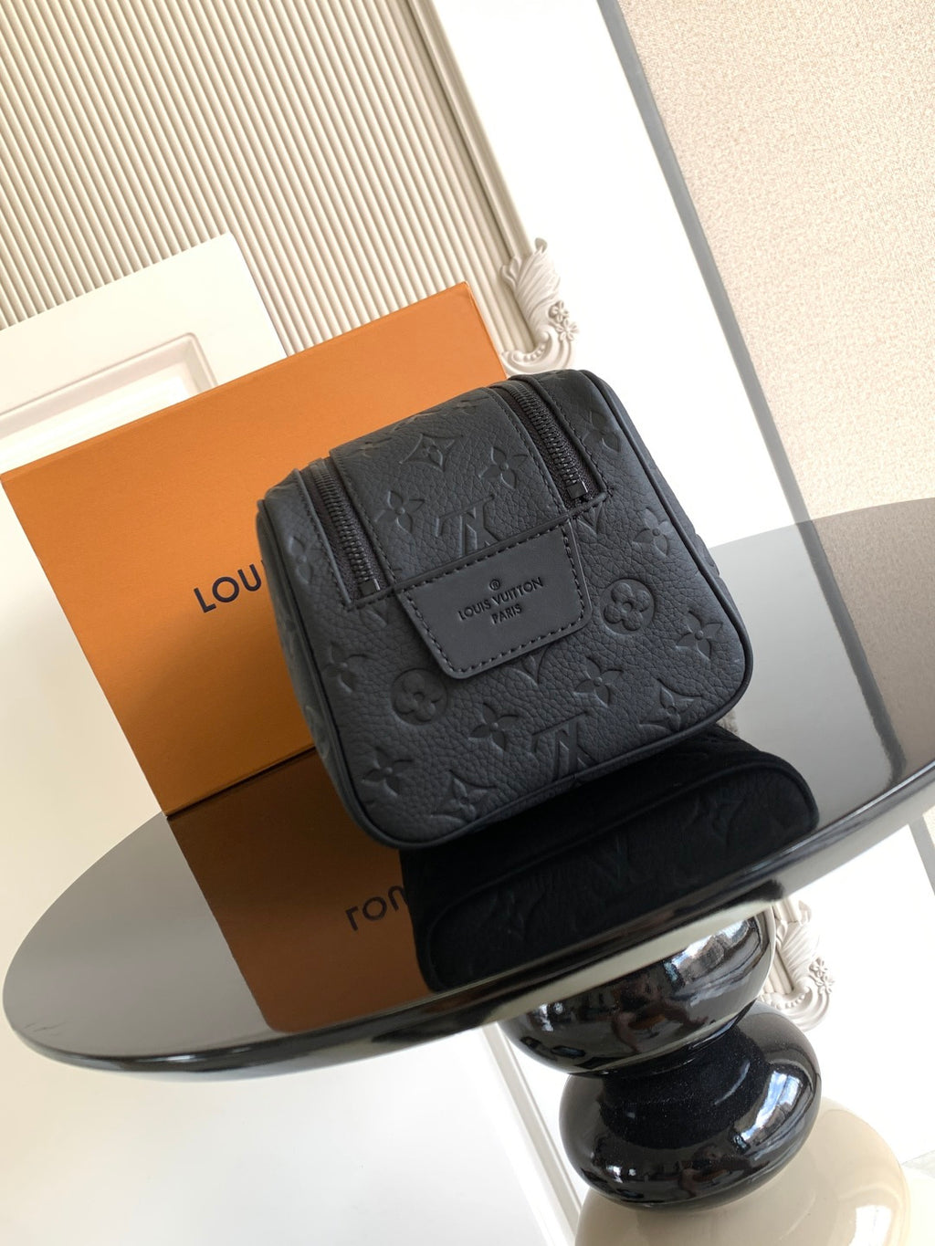 Louis Vuitton bag with dark monogram texture, front patch detail, and top zipper