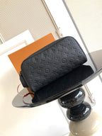 Louis Vuitton bag with embossed dark monogram, top zipper, and small hanging tag
