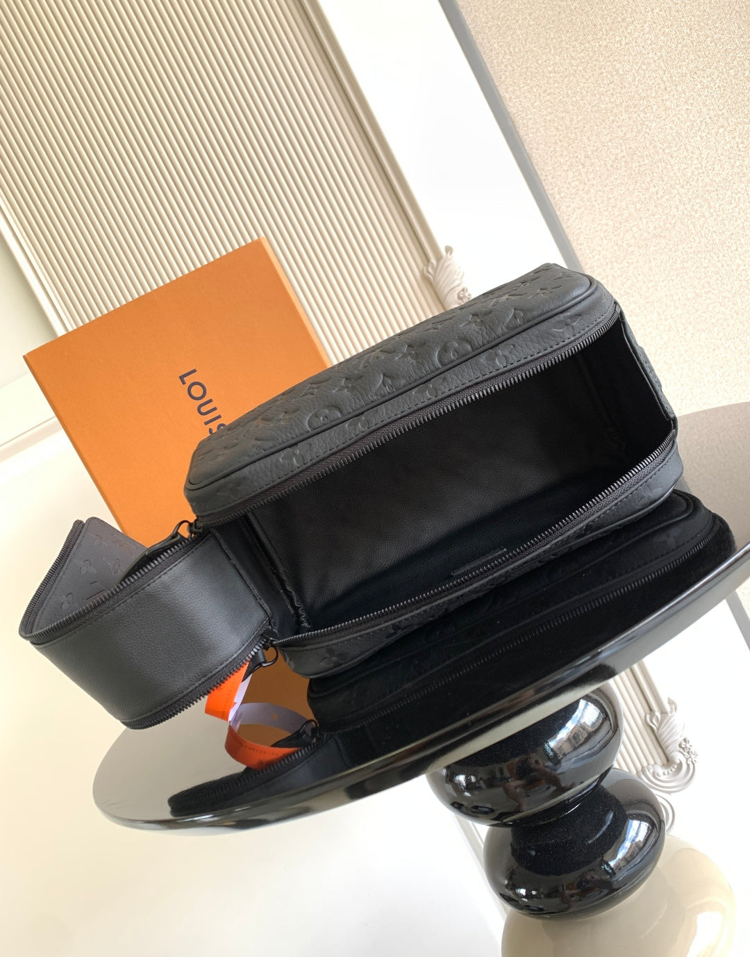 Louis Vuitton bag with black leather look, top zipper, and side strap detail