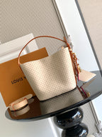 Louis Vuitton shoulder bag with tan monogram canvas, curved leather handles and tassel