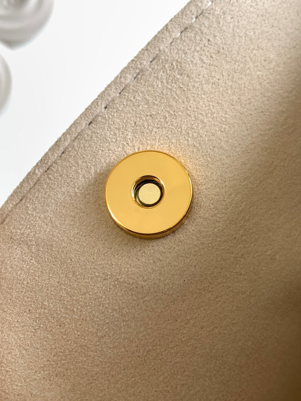 Louis Vuitton gold snap button on beige bag panel