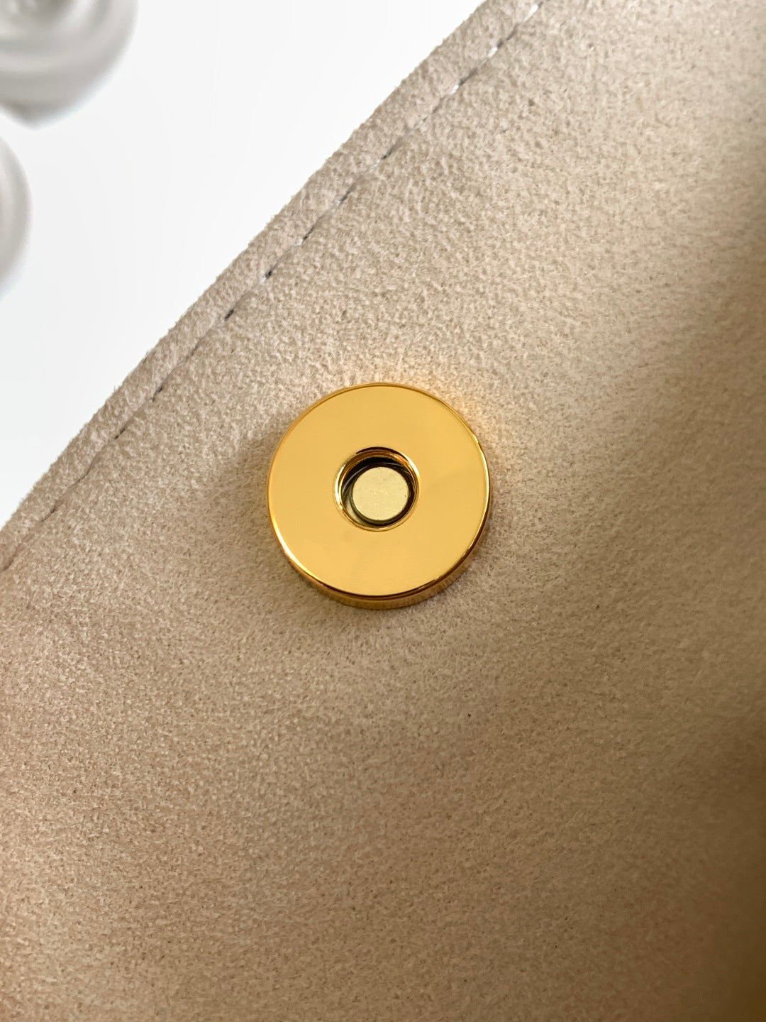 Louis Vuitton gold snap button on beige bag panel