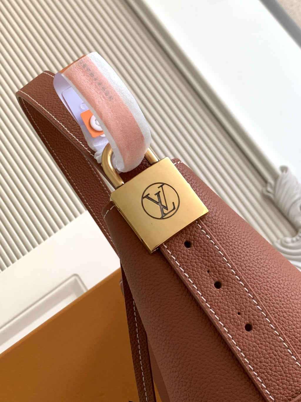 Louis Vuitton leather strap with gold padlock clasp and LV logo medallion