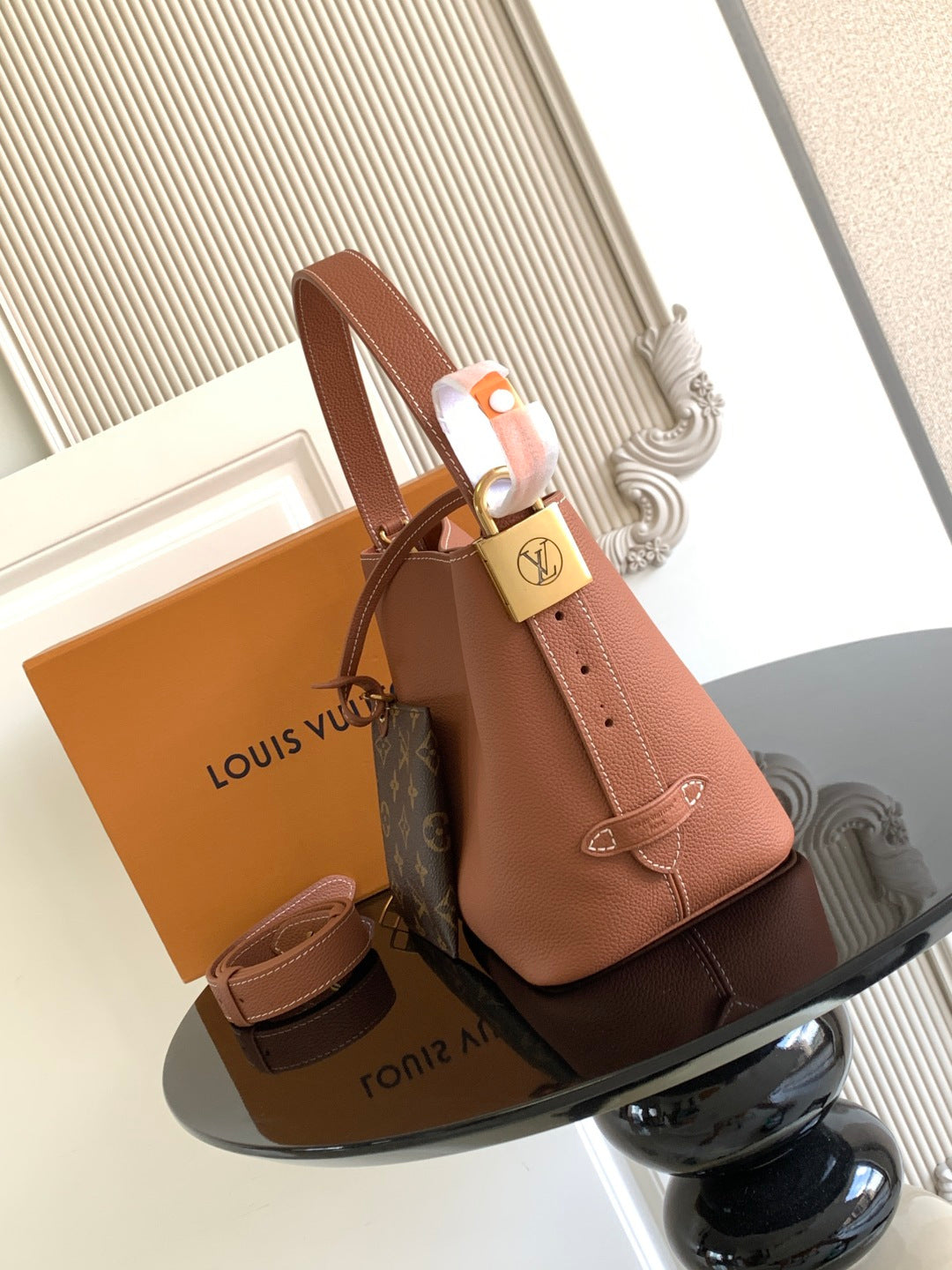 Louis Vuitton leather tote bag with shoulder strap, padlock clasp, and top handles