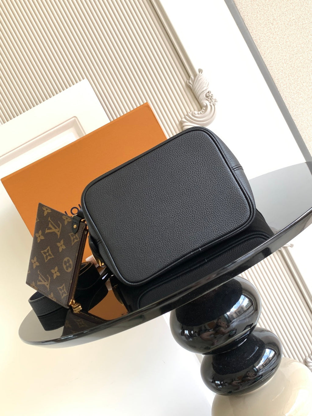 Black leather flap crossbody bag with gold-tone clasp and top handle detail.