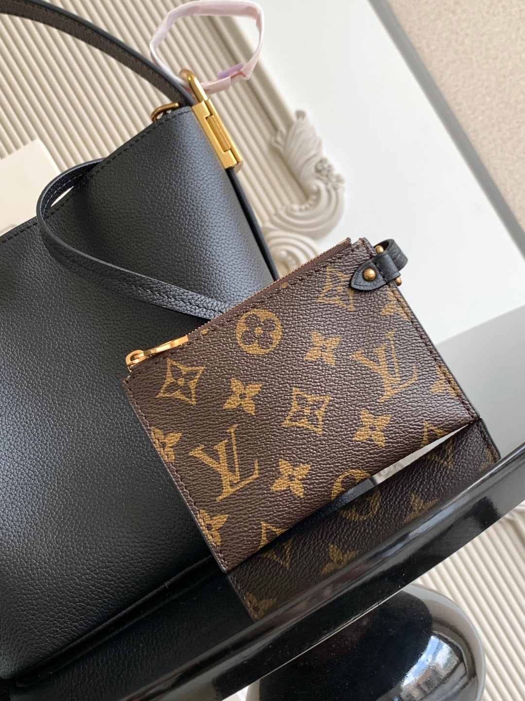 Black leather bucket bag with attached brown monogram pouch and gold hardware.