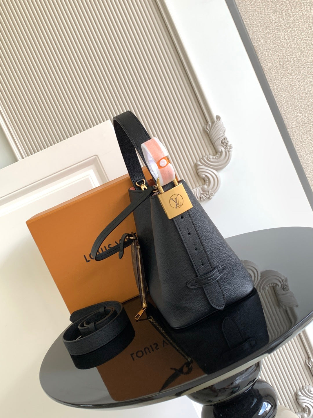 Black leather bucket bag with shoulder strap and gold-tone hardware, compact design.
