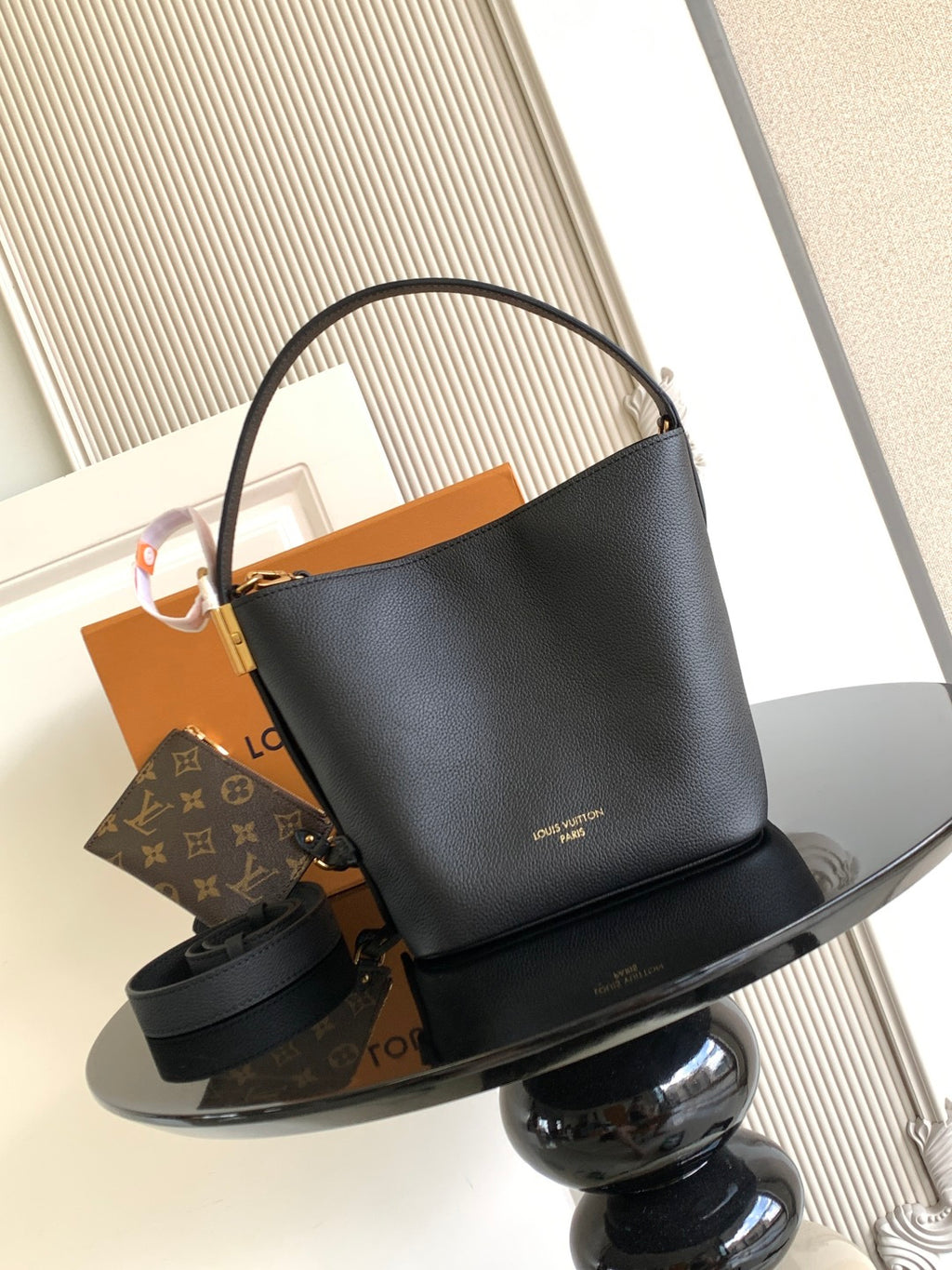 Black leather bucket bag with top handle and gold-tone hardware, open top.
