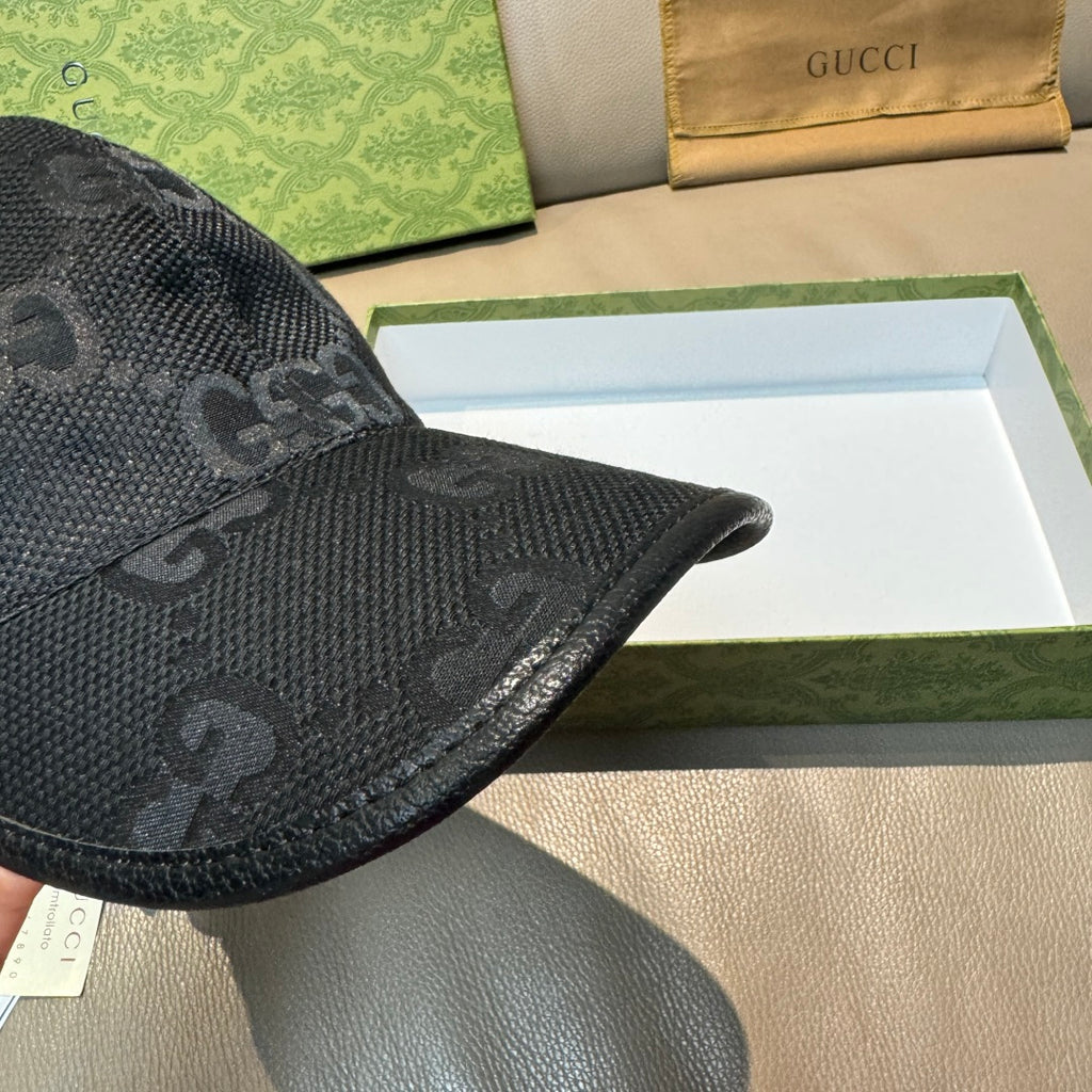 Black GG-print baseball cap close-up with textured fabric and curved brim.
