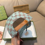 Gucci cap in light blue with red GG monogram pattern, tan leather band on top.