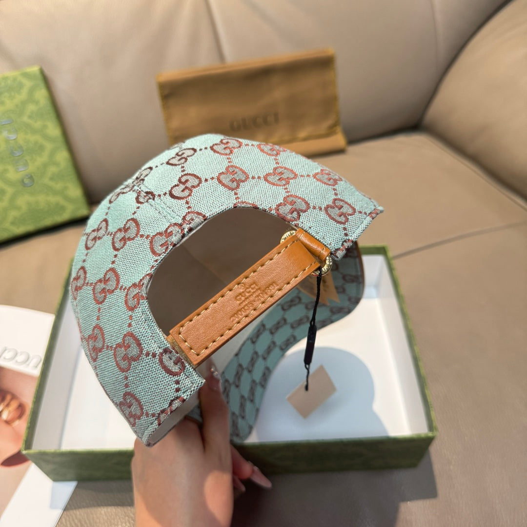 Gucci cap in light blue with red GG monogram pattern, tan leather band on top.