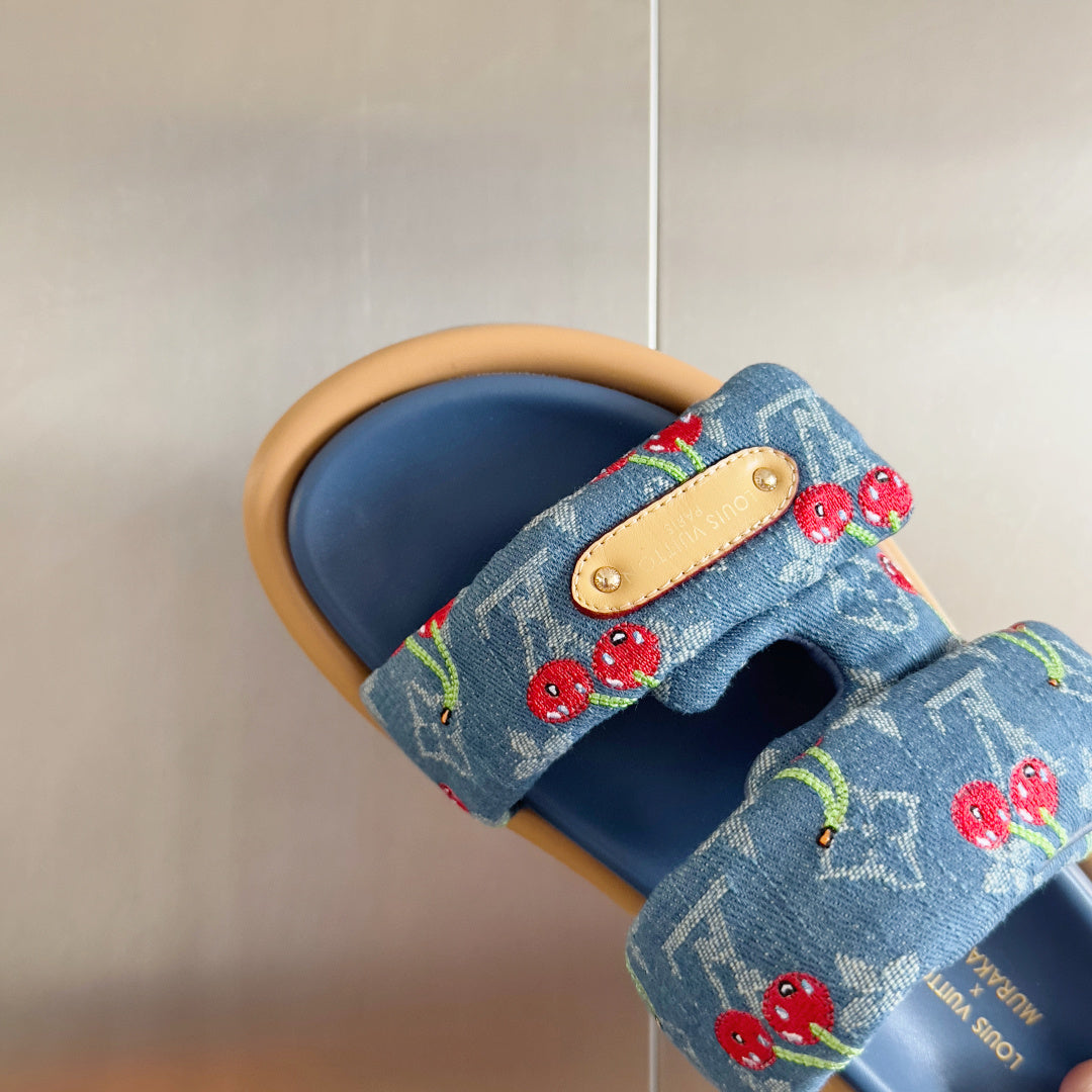 Blue Louis Vuitton slide sandal close-up with cherry print strap and tan leather tab