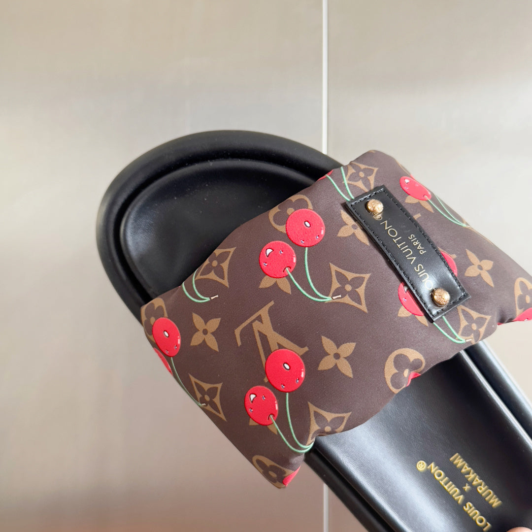 Louis Vuitton slide sandal detail: dark monogram strap with red cherries and embossed logo patch