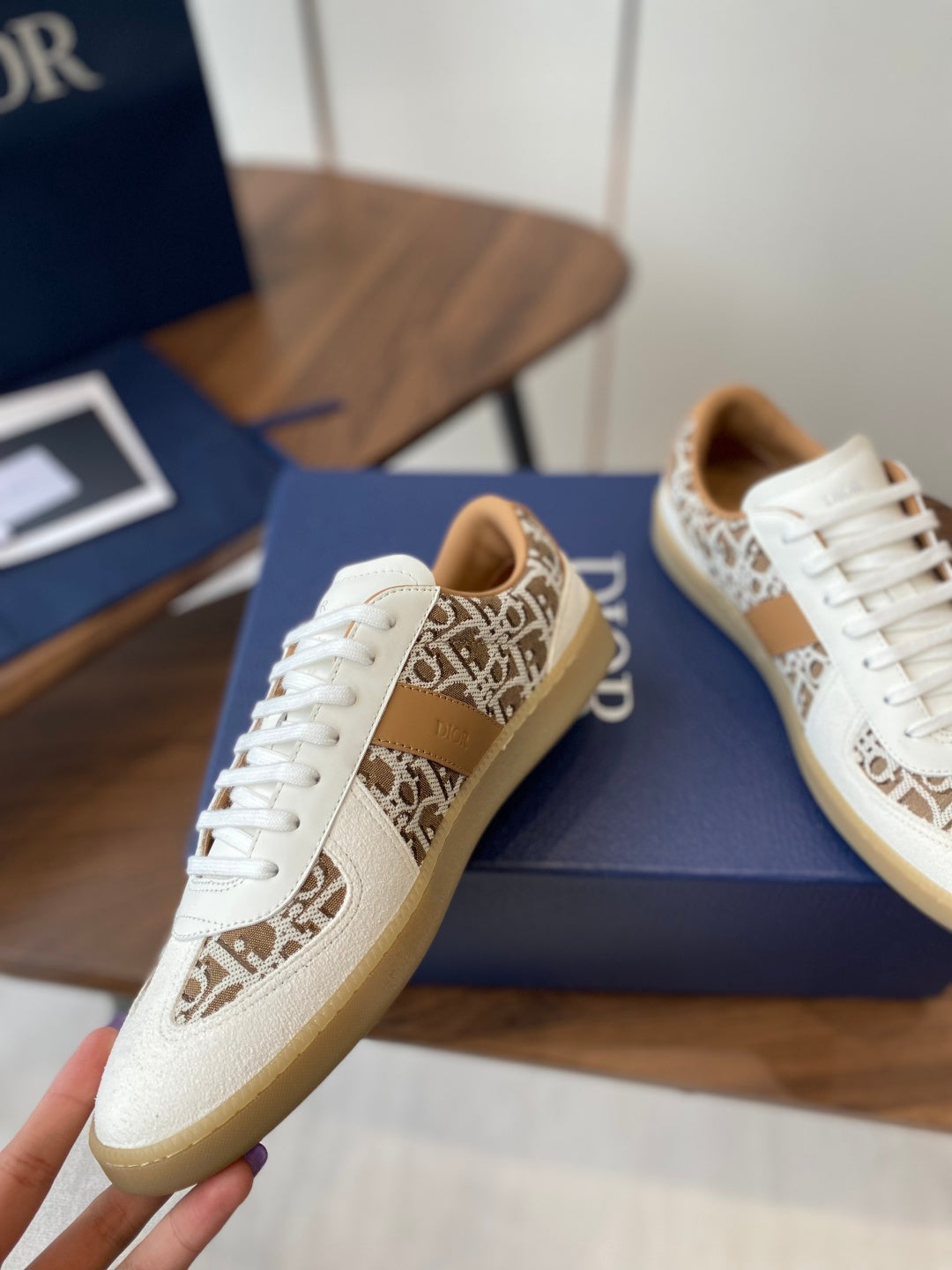 Close-up Dior unisex sneaker in white with tan monogram stripe and white laces