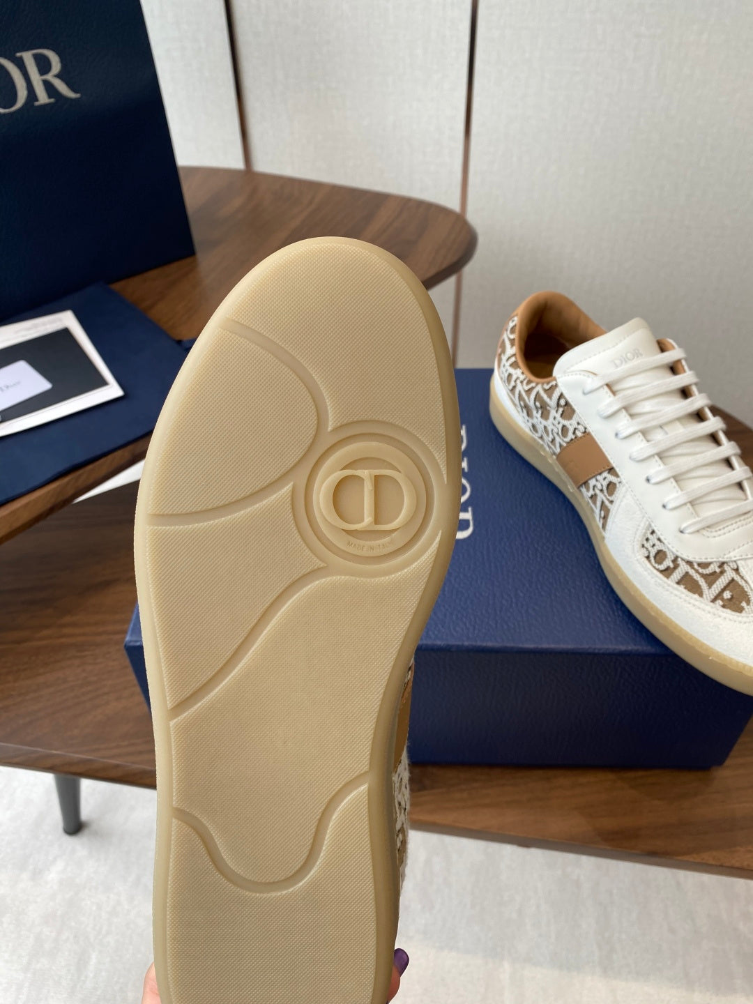 Outsole view of Dior unisex sneaker in light tan with embossed logo pattern