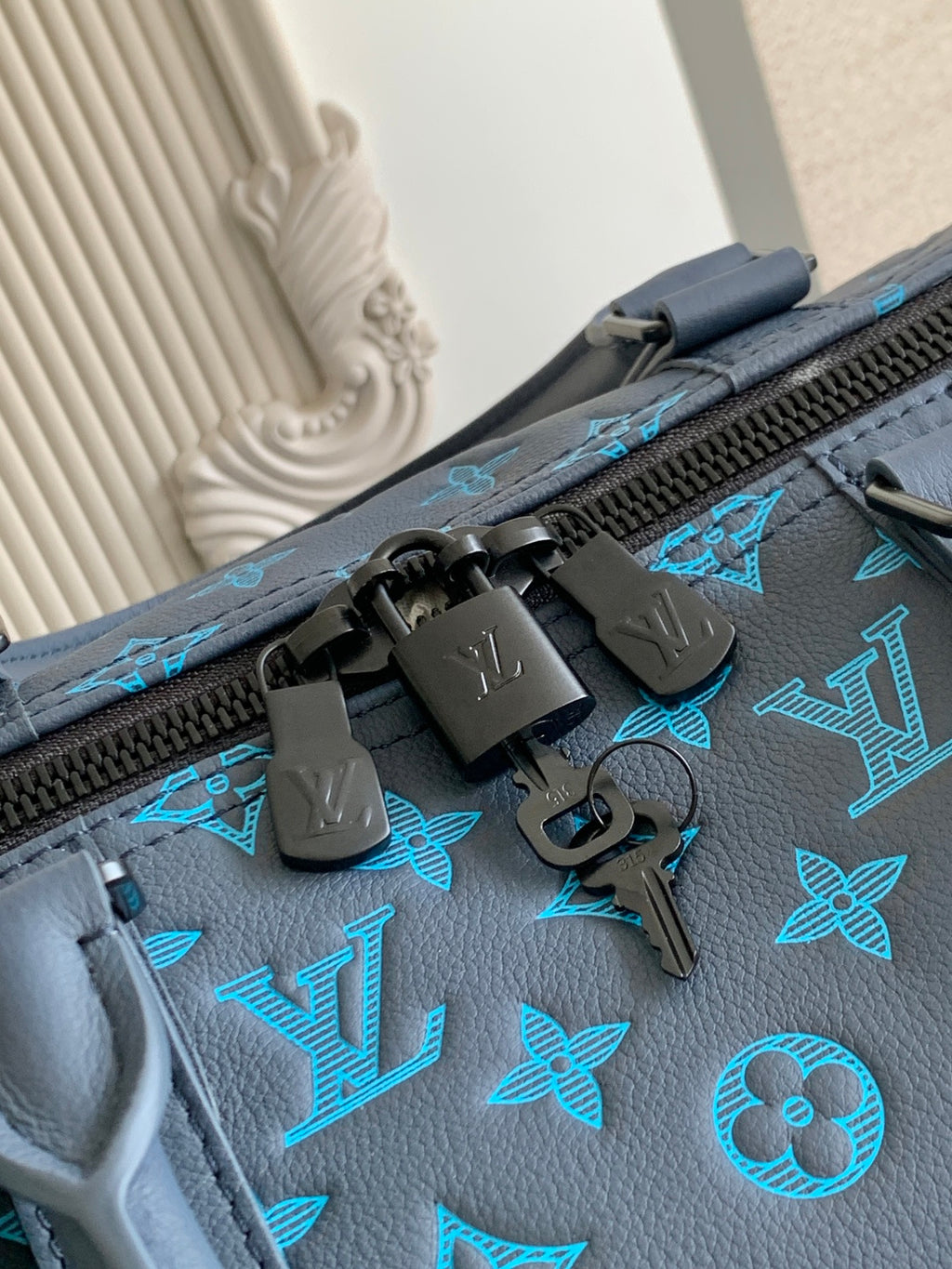 Blue monogram duffel bag close-up of zipper pull and engraved hardware
