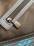 Monogram duffel bag close-up of metal zipper pull on blue canvas edge