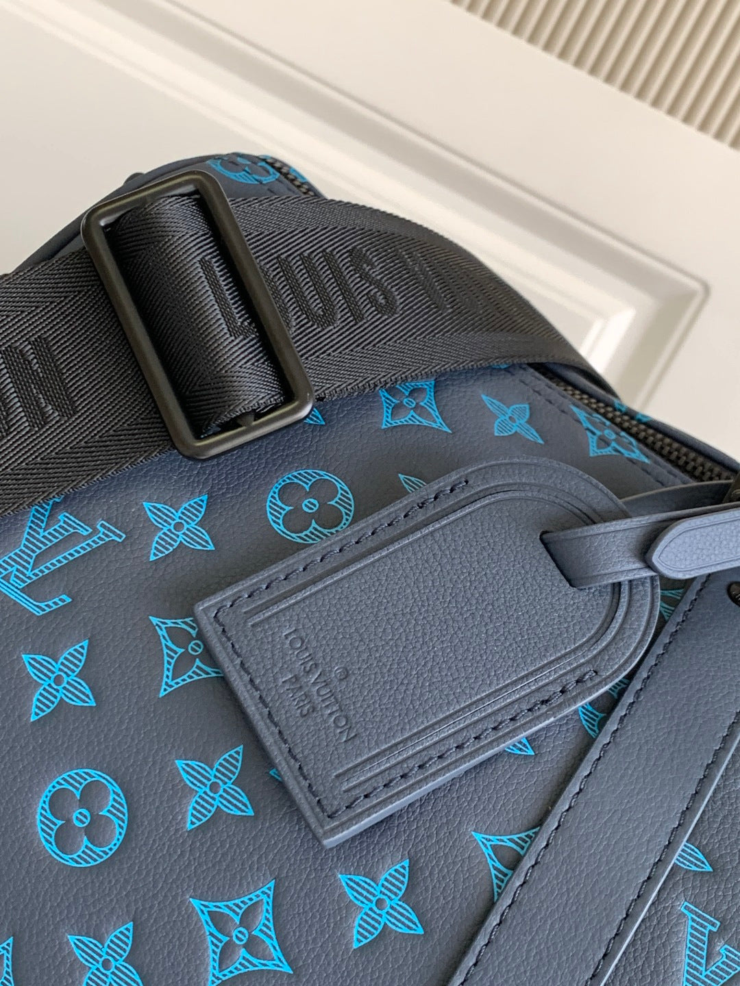 Blue monogram duffel bag close-up of embossed leather patch and strap