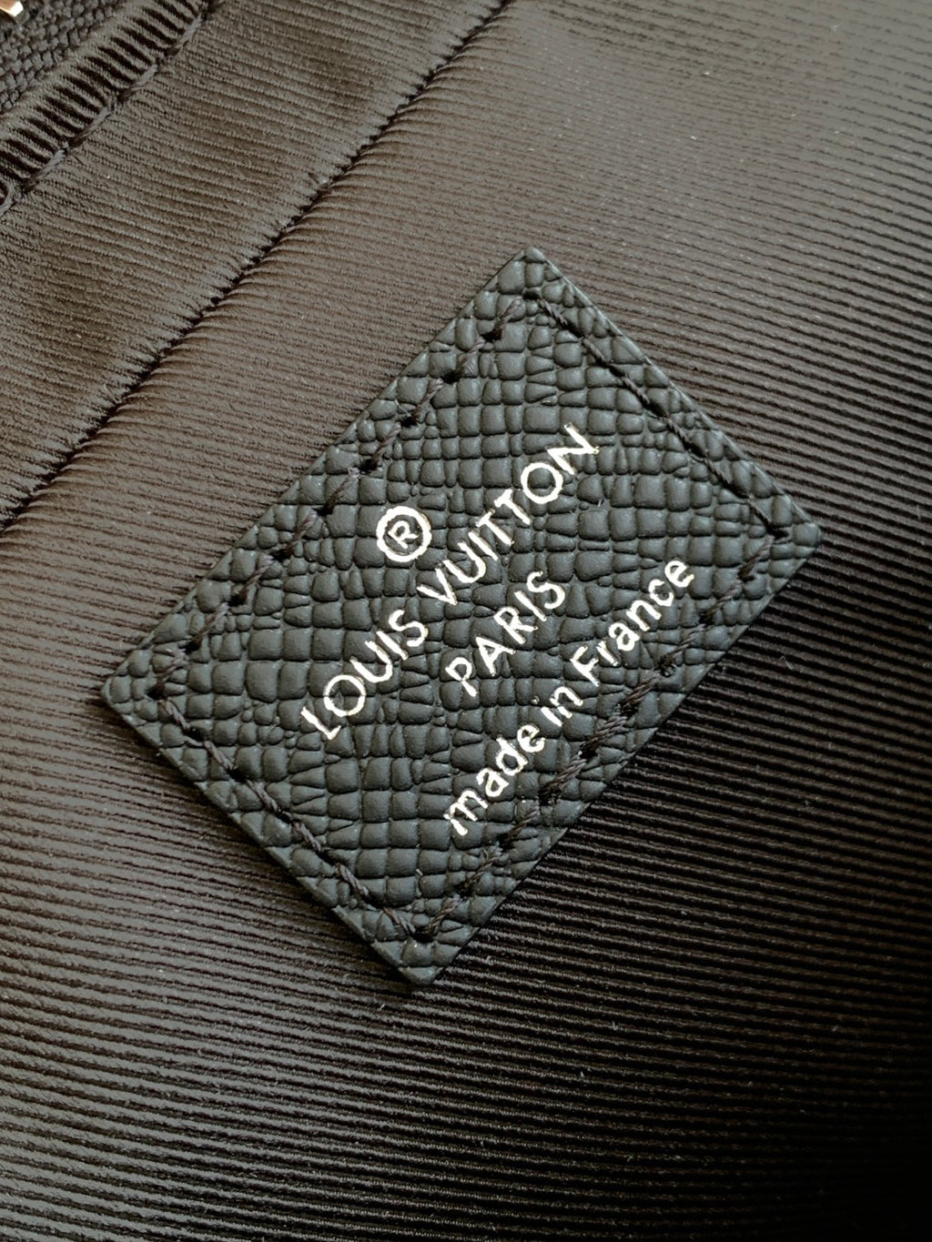 Louis Vuitton bag, black leather care label with Louis Vuitton Paris text