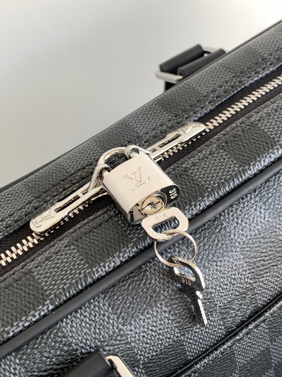 Louis Vuitton bag zipper pull with metal lock and chain, silver tone on dark gray