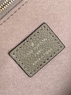 Louis Vuitton bag close-up of stitched brand label patch on taupe leather.
