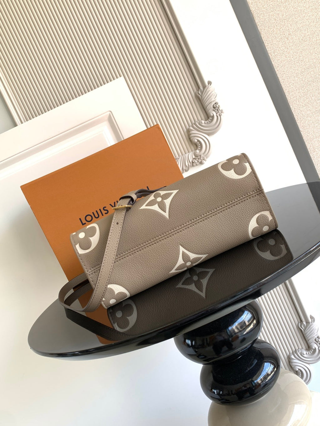 Louis Vuitton bag with monogram canvas pattern and long strap, shown folded on tray.