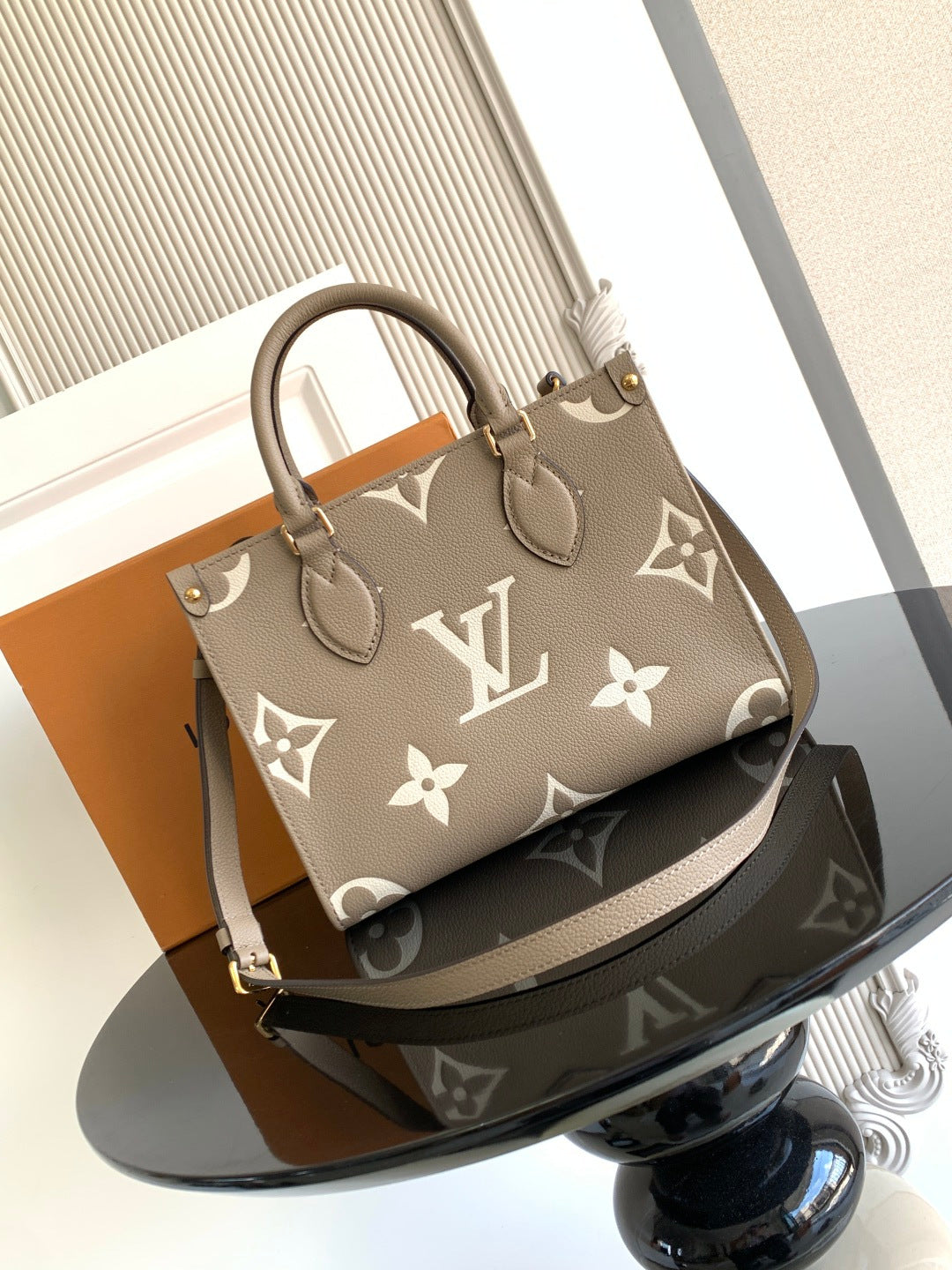 Louis Vuitton bag in gray-beige with monogram print, top handles, and structured shape.