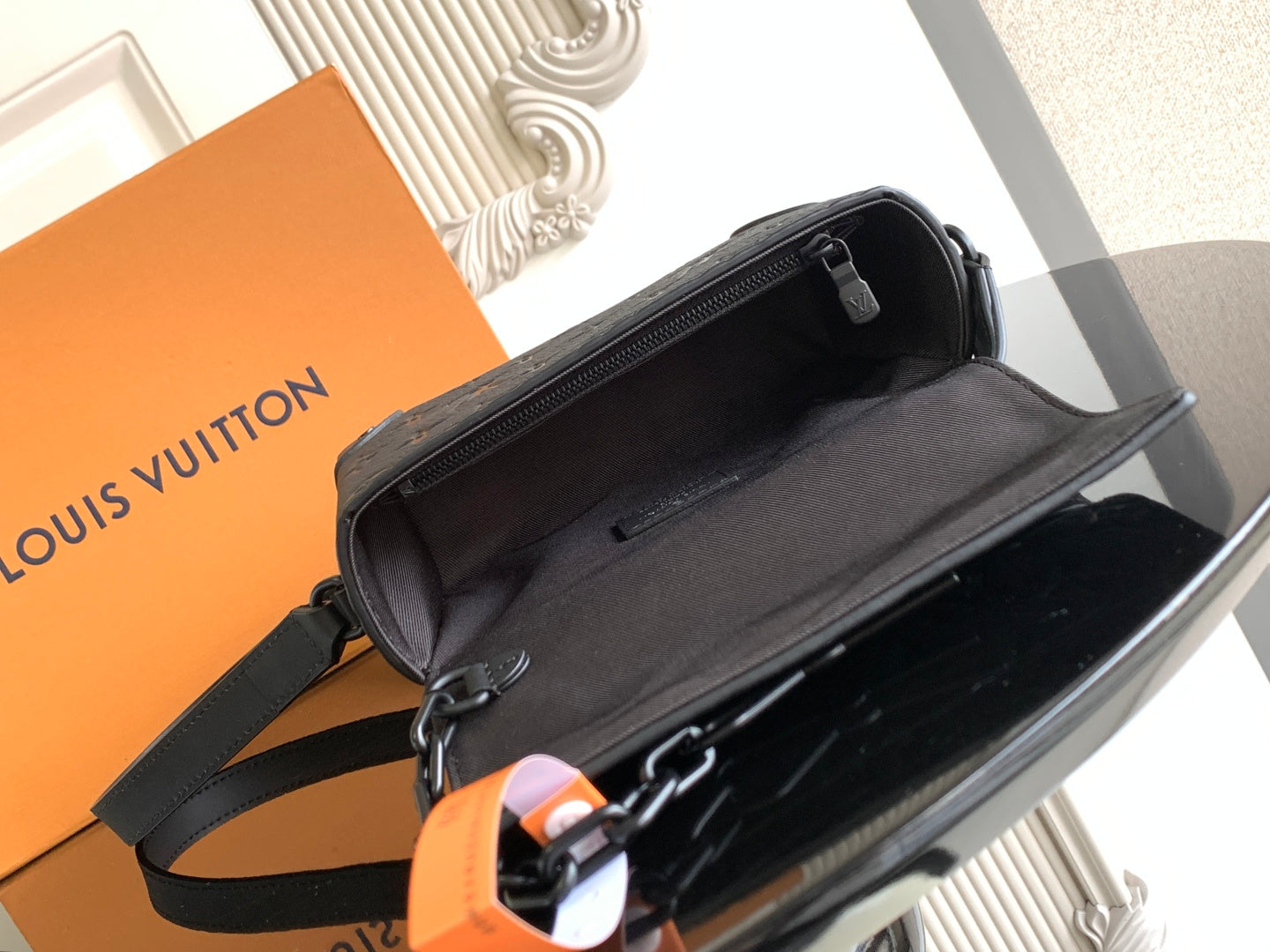 Louis Vuitton crossbody bag with open top and black interior, zipper pull visible