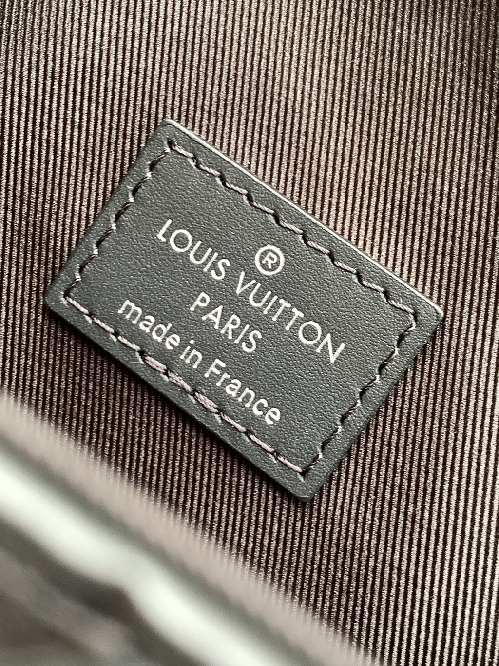 Louis Vuitton Paris made in France label on bag, stitched onto dark fabric