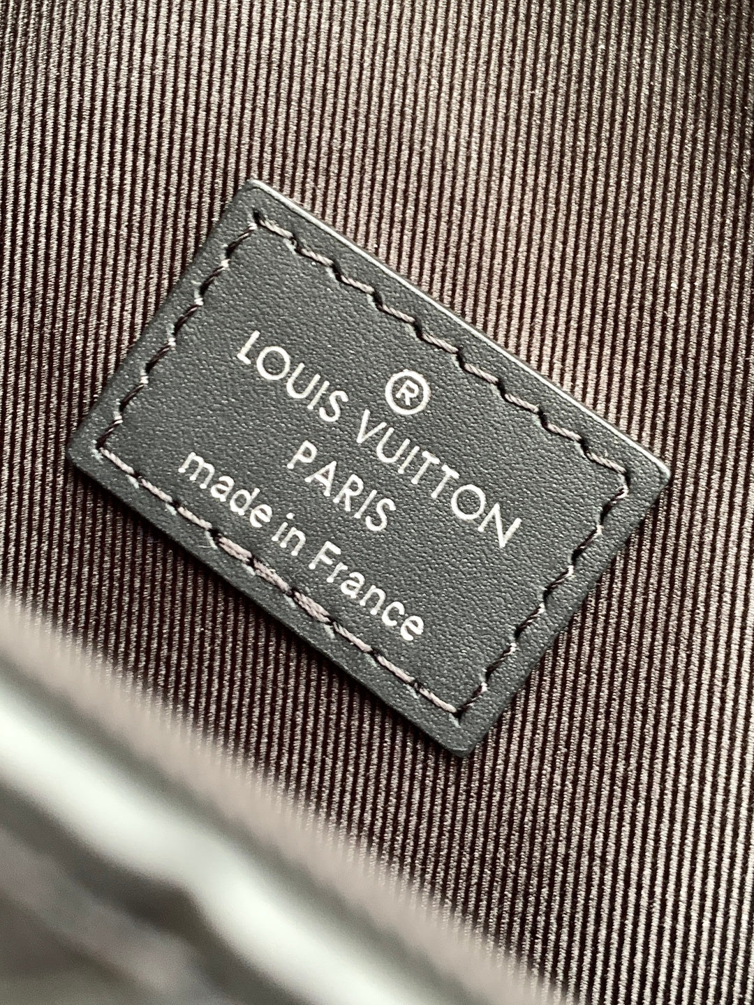 Louis Vuitton Paris made in France label on bag, stitched onto dark fabric