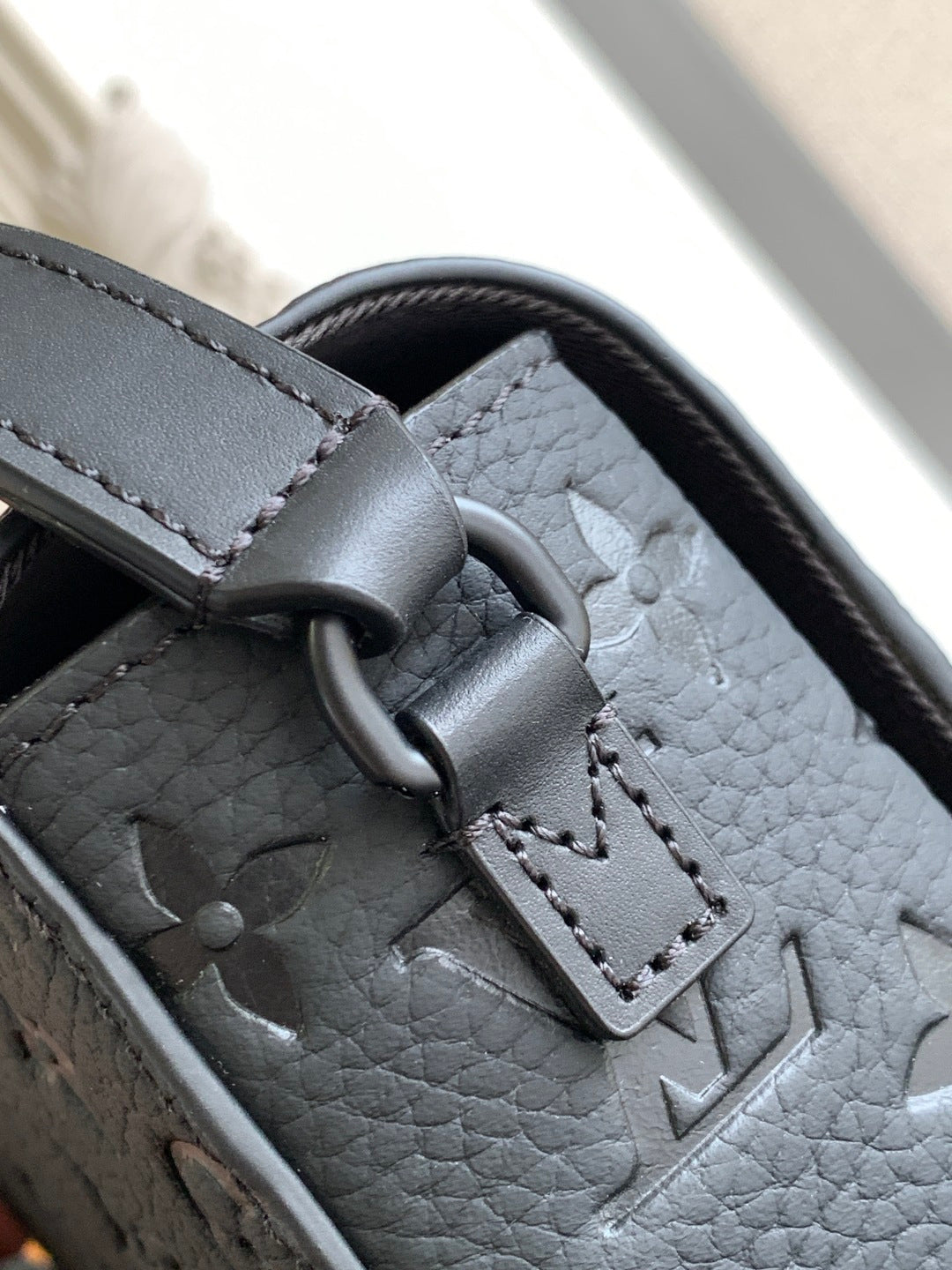 Louis Vuitton monogram bag detail with dark strap and silver-toned hardware