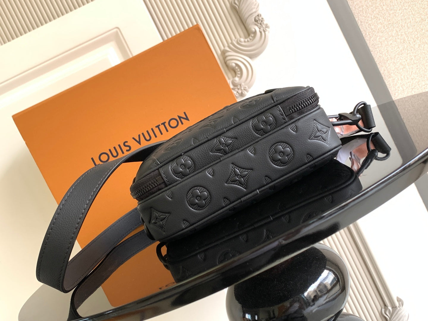 Louis Vuitton monogram crossbody bag with embossed pattern, dark strap, and zipper pocket