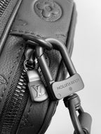 Louis Vuitton crossbody bag close-up of dark padlock and zipper pull on leather