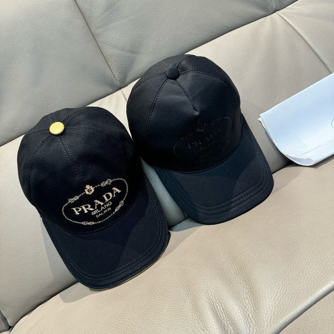 Two black baseball caps with embroidered Prada logos and gold buttons on tops.