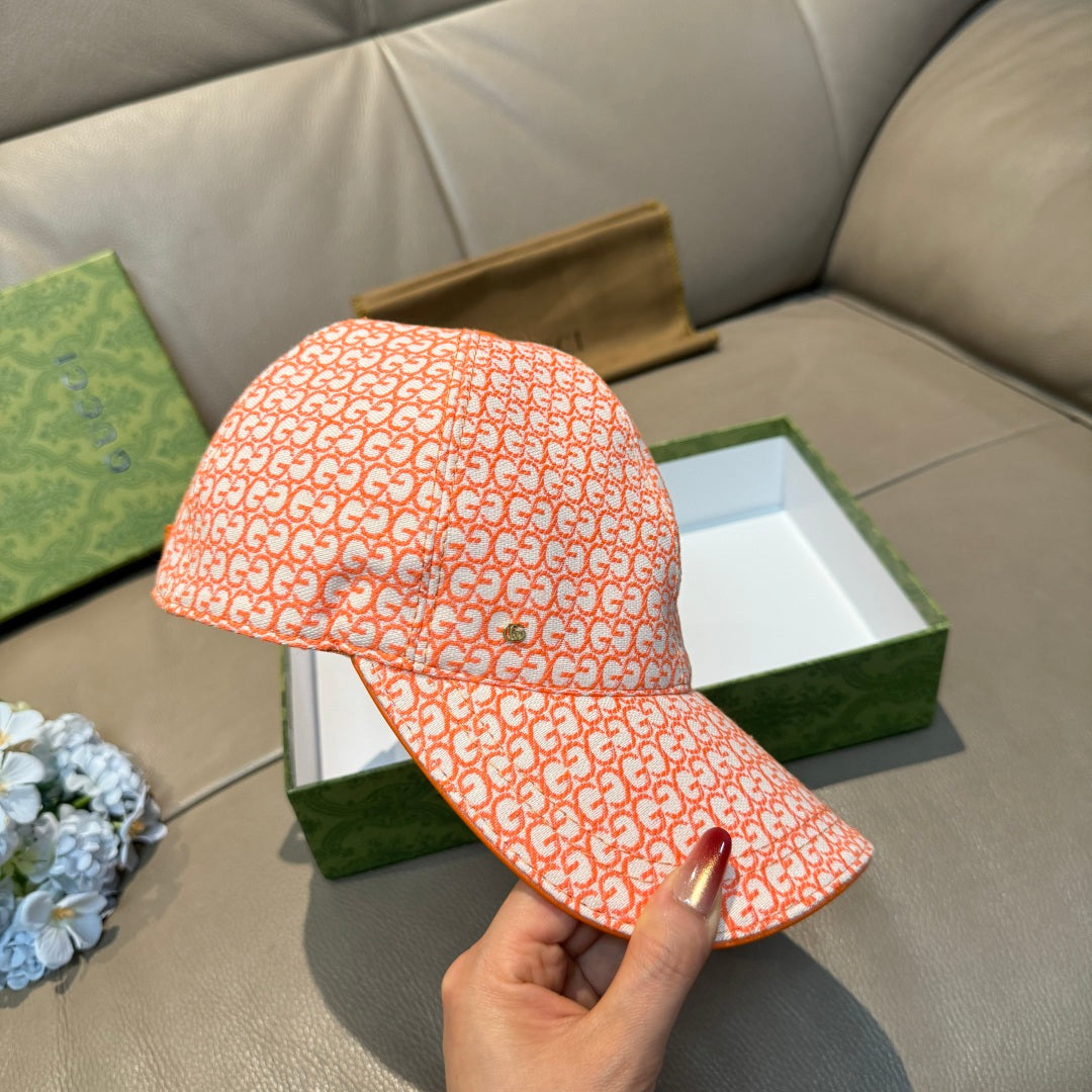 Orange GG-pattern baseball cap with curved brim, held by hand
