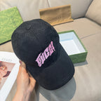 Black Gucci baseball cap held up, GG pattern with pink logo patch and curved brim