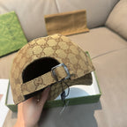 Gucci GG monogram cap with black strap and metal buckle on tan fabric