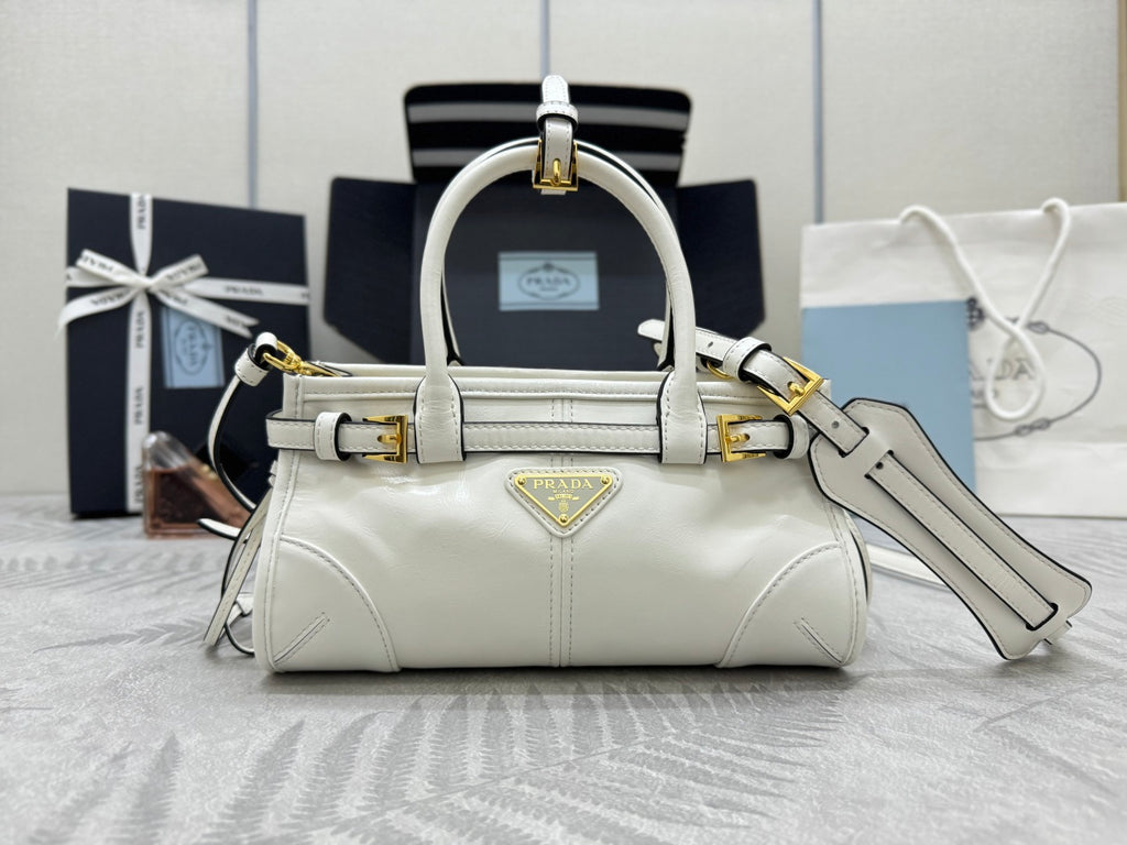 White Prada mini handbag with top handles, gold hardware, and detachable shoulder strap.