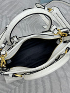 Open-top white Prada handbag interior with zipper, lining, and gold-tone hardware.